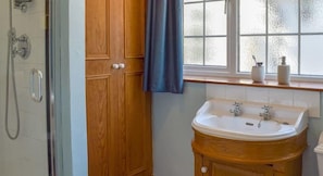 A bathroom with a glass shower enclosure, wooden door, and a sink with a mirror. - Turpins Ride (Chalfont St Giles)