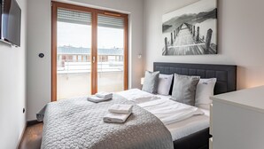 Une chambre d’hôtel avec un lit, une télévision, un tableau et une vue sur un balcon.