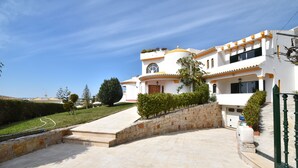 A large, white building with a curved roof and orange accents, featuring a stone pathway leading to the entrance. - Villa Atlantida, a charming hillside villa with a fabulous pool, great sea view. (Albufeira)