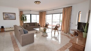 A spacious living room with a sofa, chairs, a glass coffee table, and a TV. - Villa Atlantida, a charming hillside villa with a fabulous pool, great sea view. (Albufeira)