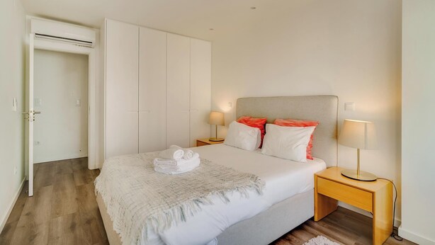A bedroom with a bed, nightstands, a wardrobe, and a door.