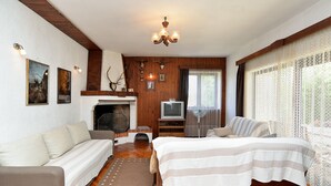 Ein gemütliches Zimmer mit Kamin, Fernseher und einem Bett mit gestreifter Bettdecke.