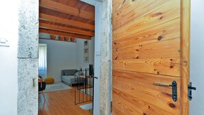 A wooden door with a metal handle, a stone wall, and a view into a room with a sofa, a small table, and a window. - House 1953/24881 (Istria - Vodnjan), 6000m from the beach (Vodnjan)