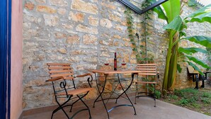 A stone wall with a wooden bench and table, a bottle of wine, and a large plant. - House 1953/24881 (Istria - Vodnjan), 6000m from the beach (Vodnjan)