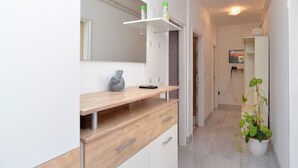 Een moderne badkamer met een houten wastafelmeubel, een spiegel en een potplant.