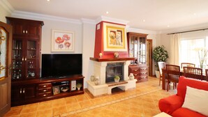 A living room with a fireplace, television, and a red sofa. - 1128 Villa AndreaSol (Frigiliana)