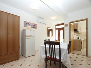 A compact kitchen with a refrigerator, a dining table with chairs, and a wooden wardrobe. - Apartment 1965/25900 (Istria - Pula), 3250m from the beach (Pula)