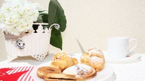 Una mesa blanca con un plato de pasteles, una taza blanca y un paño a rayas.