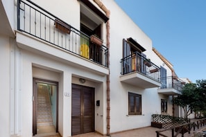 Stylish two-story residence with a modern design, featuring a double door and two balconies with potted plants.