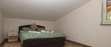 Un dormitorio con cama, mesita de noche y ventana.