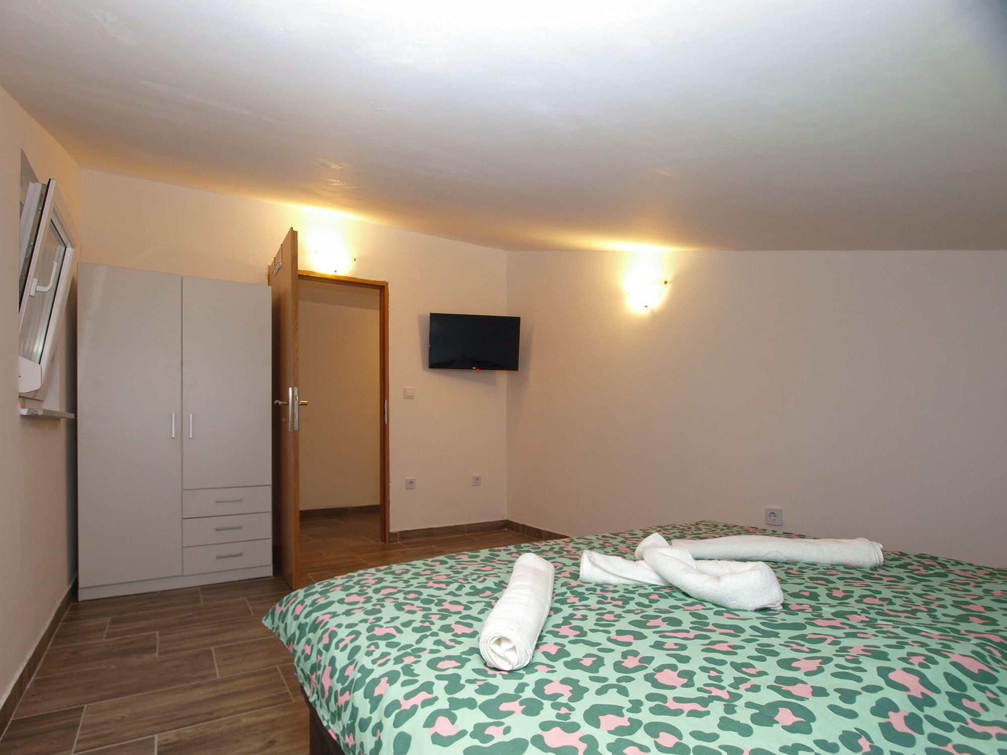 Une chambre d’hôtel comprenant un lit, une armoire, un téléviseur et une porte donnant sur une autre pièce.