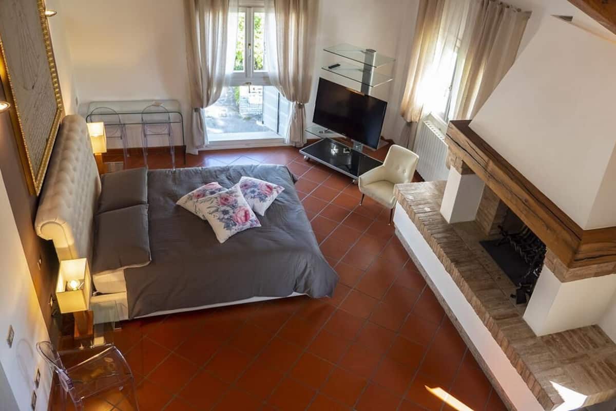 Ein Schlafzimmer mit Bett, Fernseher, Kamin und Balkon.