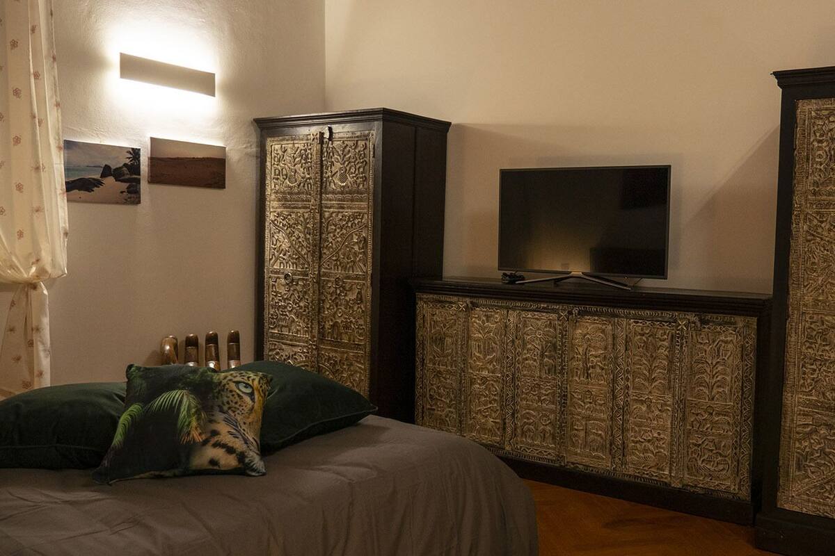 Ein Schlafzimmer mit einem Bett, einem Fernseher auf einem Schrank und einer dekorativen Wandverkleidung.