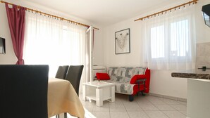 Ein modernes Wohnzimmer mit einer Couch, Sesseln, einem Couchtisch und einem Essbereich mit Tisch und Stühlen.
