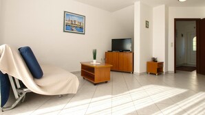 A living room with a reclining chair, a television on a wooden cabinet, and a painting on the wall. - Apartment 1978/26796 (Istria - Poreč), 5000m from the beach (Porec)