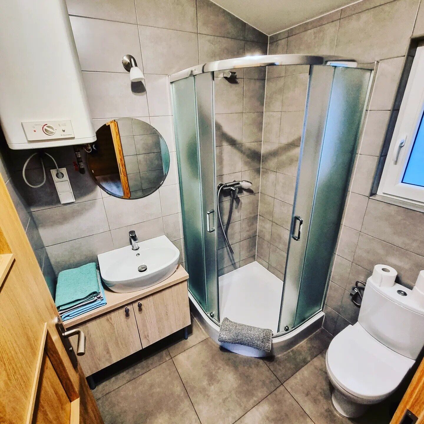 Un baño moderno con ducha de vidrio, un lavabo con espejo y un inodoro.