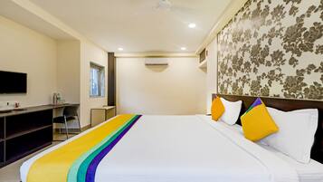 Habitación de hotel con cama, escritorio, silla, televisor y ventana.