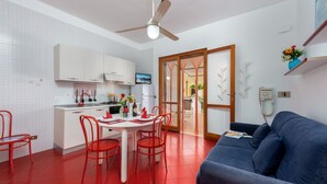 A compact living space with a kitchenette, dining area, and a sofa. - I Tre Golfi Faro Blu Apartment (San Vito Lo Capo)