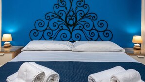 A hotel room with a large bed, two bedside lamps, and a decorative metal headboard. - I Tre Golfi Faro Blu Apartment (San Vito Lo Capo)