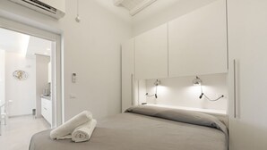 Ein modernes Schlafzimmer mit Bett, Nachttischlampen und Blick ins Bad.