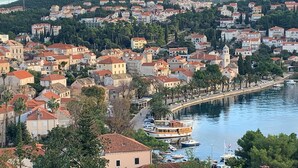 A coastal town with buildings along the waterfront, a prominent church, and a large boat docked near the shore. - Fox Apartments (Konavle)