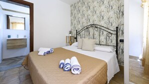 Una camera d'albergo con un letto, un bagno con uno specchio e carta da parati decorata.