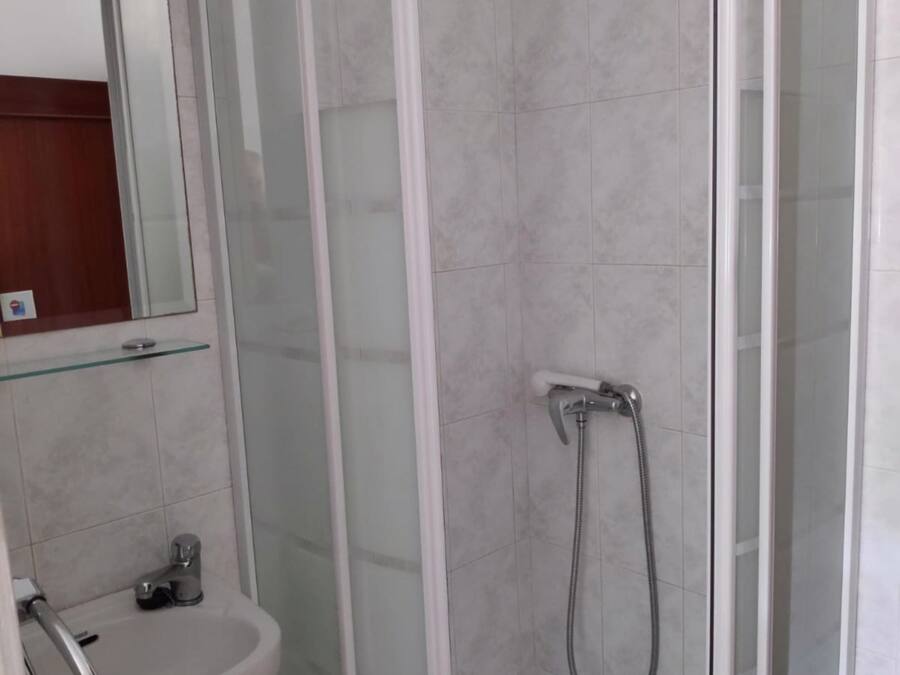 Un bagno moderno con doccia vetrata, lavandino bianco e specchio sopra il lavandino.