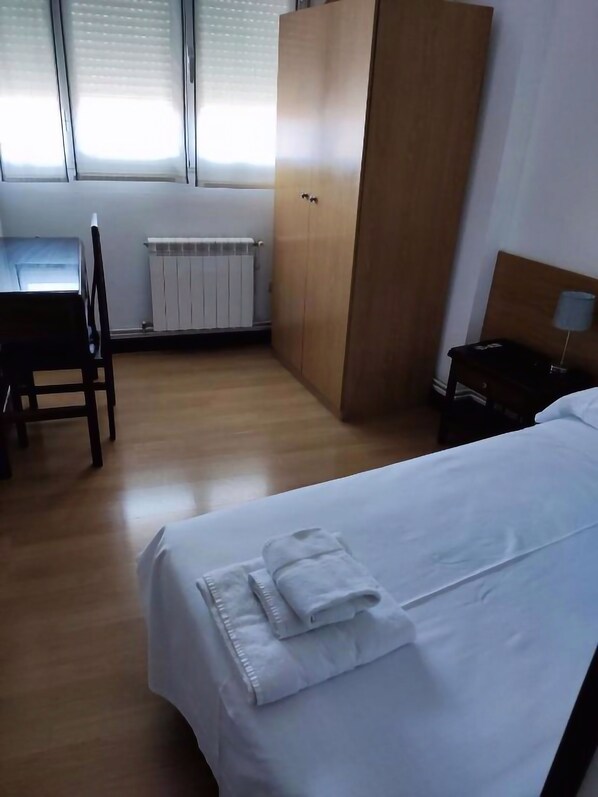 A hotel room with a bed, a desk, and a wardrobe.