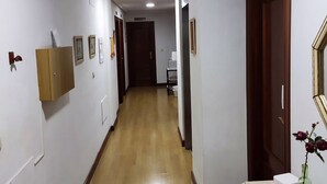 A hallway with wooden flooring, white walls, and a wooden door at the end. - Pensión Las Matillas (Miranda de Ebro)