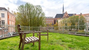 A park with a wooden bench and a metal fence.