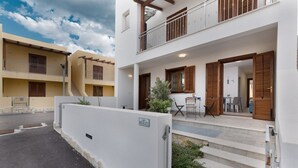 Un immeuble résidentiel de deux étages doté d’un balcon, d’un petit espace extérieur aménagé en coin salon et d’une entrée bien visible.