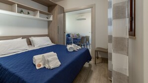 Une chambre d’hôtel avec un lit, un bureau et une chaise. Il y a des serviettes sur le lit.