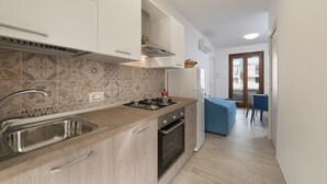 Une cuisine moderne dotée d’une cuisinière à gaz intégrée, d’un évier en acier inoxydable et de meubles blancs.