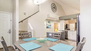 A dining area with a round table, blue placemats, and a decorative centerpiece.
