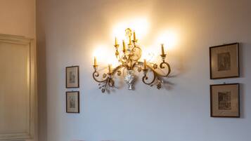 Una habitación con sofá a rayas, candelabro fijado a la pared y cuadros enmarcados.