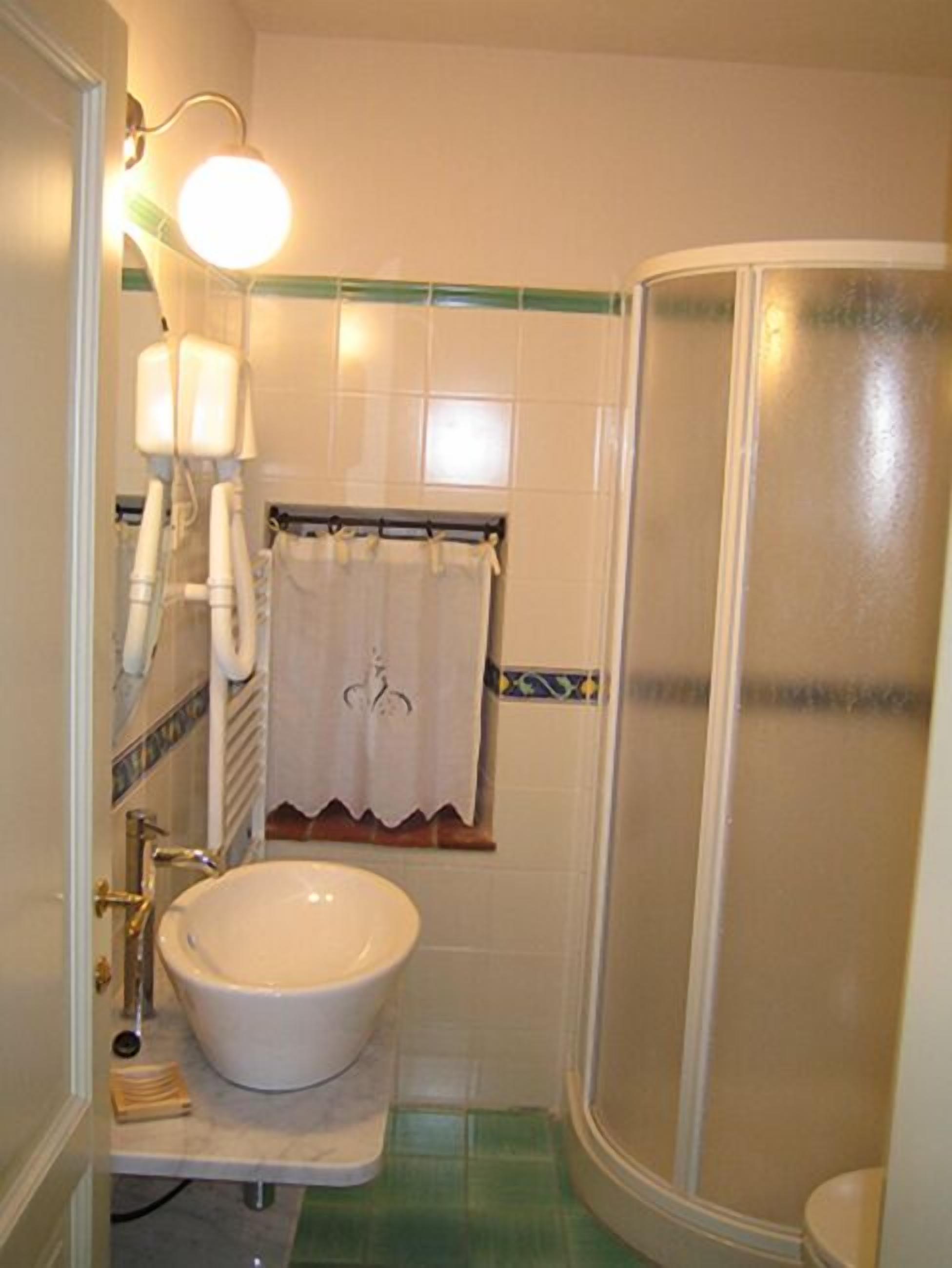 A bathroom with a white sink, a shower, and a towel hanging on a rack.
