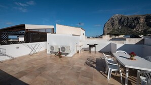 A rooftop terrace with a dining area, air conditioning units, and a view of a mountain.