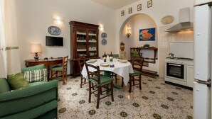 Ein Essbereich mit einem runden Tisch, Stühlen, einem Schrank und einem Fernseher an der Wand.