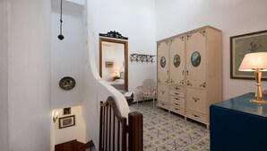 Eine Treppe führt zu einem Raum mit einem gemusterten Boden, einem großen Schrank mit mehreren Türen und einem gerahmten Bild an der Wand.