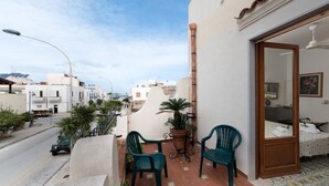Ein Balkon mit zwei Stühlen, einem Blumentopf und Blick auf die Straße und die Häuser.