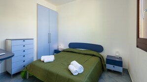 Une chambre à coucher comprenant un lit, un bureau, une armoire et une table de chevet.