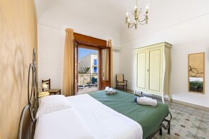A hotel room with a bed, a wardrobe, a chair, a small table with a lamp, and a view of the outside balcony. - I Tre Golfi Pegaso Apartment (San Vito Lo Capo)