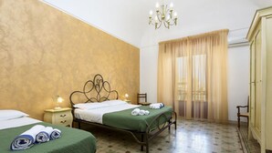 Ein Hotelzimmer mit zwei Betten, einem Chandelier, einem Schrank und einem Fenster mit Vorhängen.
