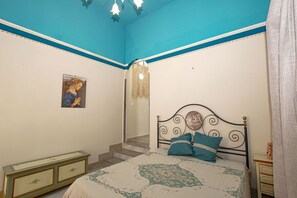 Une chambre à coucher comprenant un lit, une commode et un escalier menant à une autre pièce.