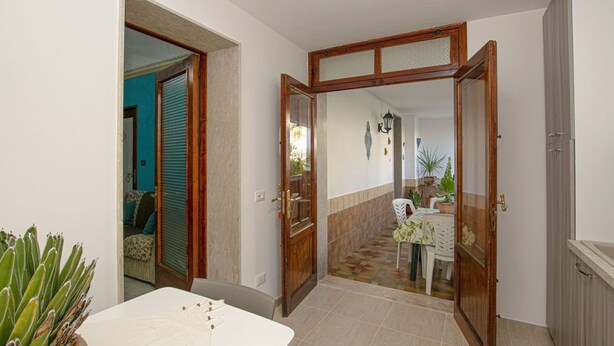 A hallway with a white table, a wooden door, and a view into a dining area with a table and chairs.