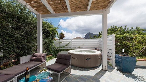 An outdoor patio with a hot tub, lounge chairs, and a pergola. - I Tre Golfi Villa Iride (San Vito Lo Capo)