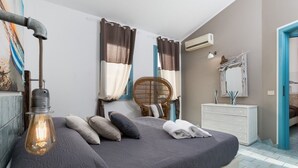 A bedroom with a bed, a dresser, a mirror, and a wall-mounted air conditioner. - I Tre Golfi Villa Iride (San Vito Lo Capo)