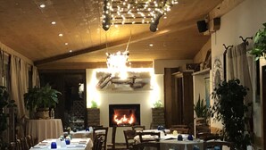 A restaurant with tables set for dining, a fireplace, and hanging lights. - Osteria e Locanda del Viaggiatore (Russi)