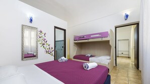 Ein Hotelzimmer mit einem großen Bett, zwei Einzelbetten, einem Spiegel und einer Badezimmertür.