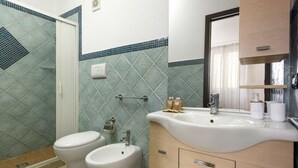 Ein Badezimmer mit Dusche, zwei Toiletten, einem Waschbecken und einem Spiegel.